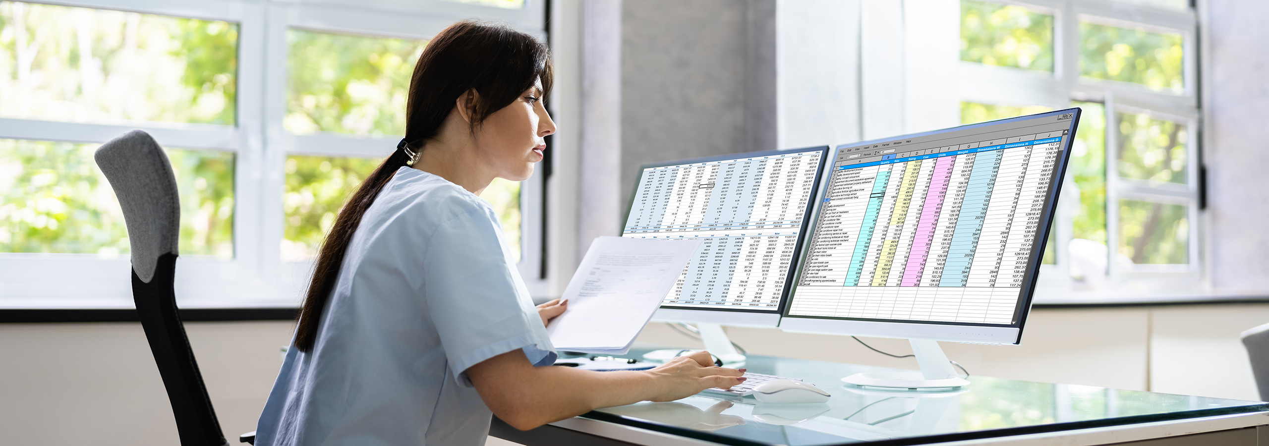 Healthcare professional reviewing spreadsheets on dual monitors, representing medical coding and IDRE claim submission error prevention.