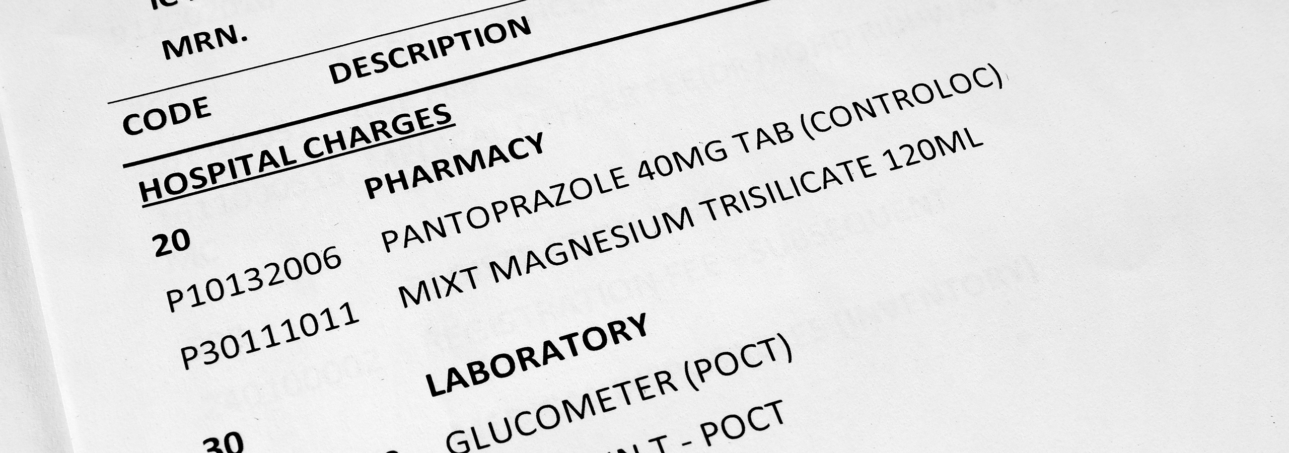 Close-up of hospital charges and medical billing codes for pharmacy and laboratory services, illustrating medical review and payment integrity.