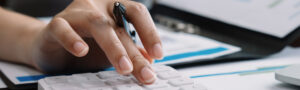 Close-up of hand using calculator to review finances, symbolizing FHAS commitment to fast refunds and accurate money management for payers and providers.