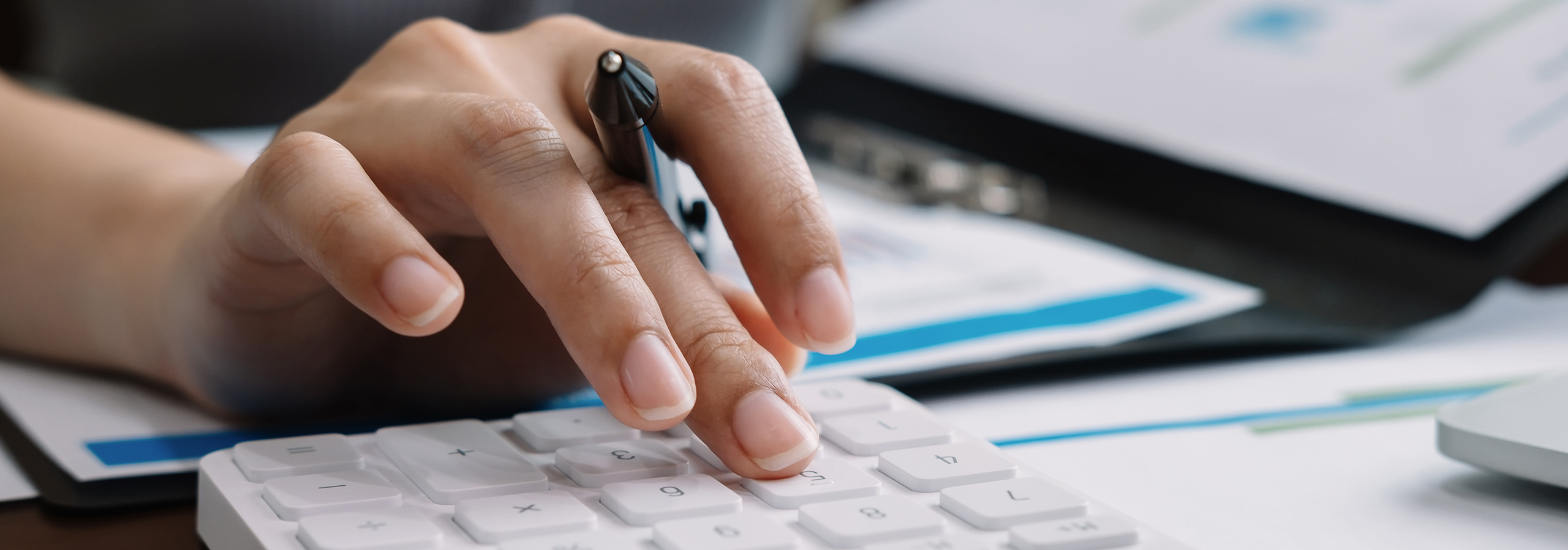 Close-up of hand using calculator to review finances, symbolizing FHAS commitment to fast refunds and accurate money management for payers and providers.